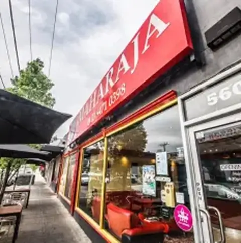 Street view of a restaurant storefront with red signage and outdoor walkway